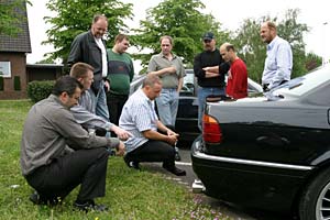 Die Teilnehmer betrachten die Auspuffanlage des BMW 740i